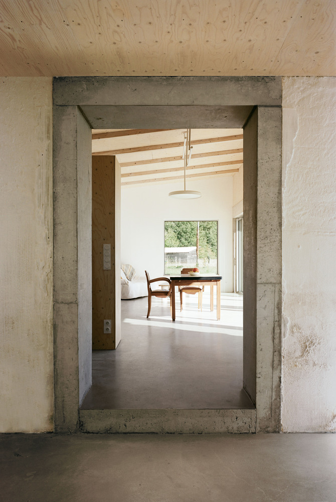 Vista interior de la transformación de un granero en una casa de vacaciones en Francia de Migeon Architecture.  Detalle de jamba y dintel de hormigón